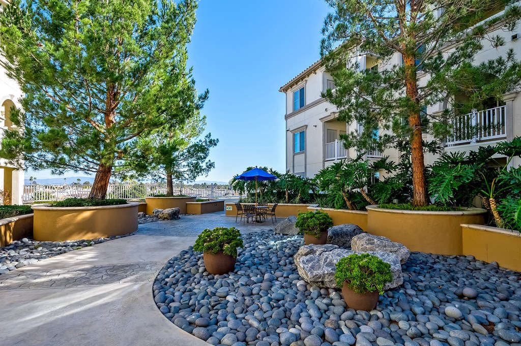 a patio with trees and rocks and a building in the background