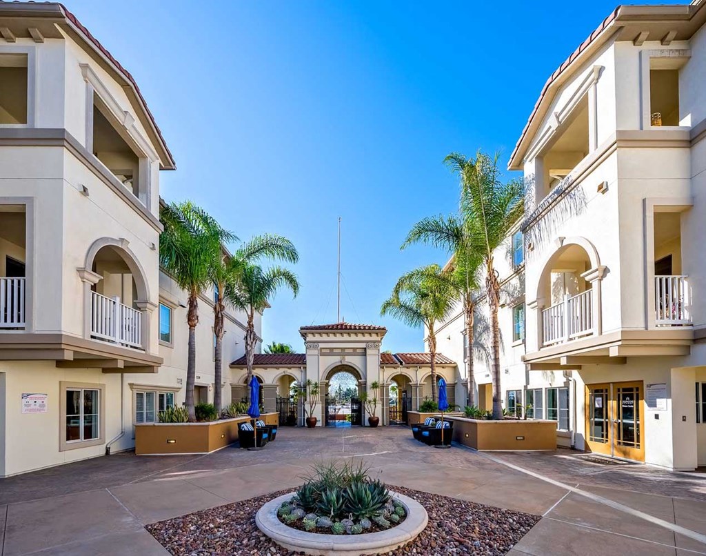 a courtyard with palm trees in the middle of some apartments