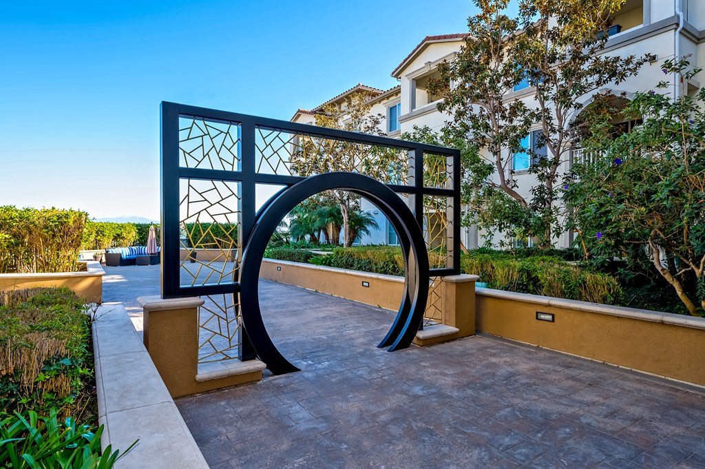 a large metal archway on a patio with buildings in the background