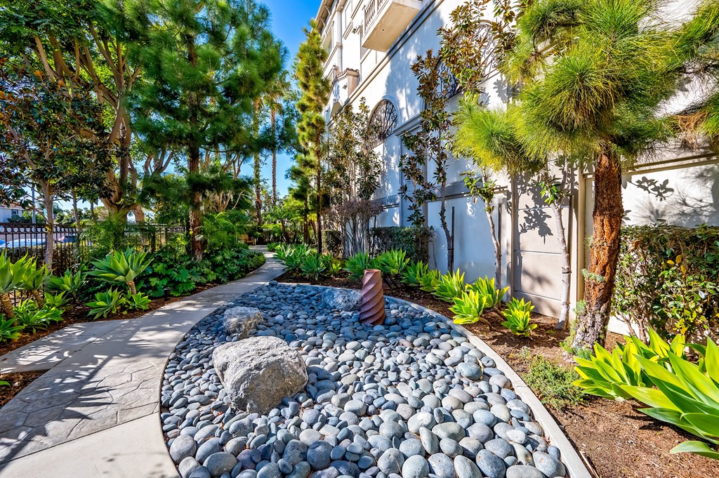 a walkway with rocks and trees in front of a building
