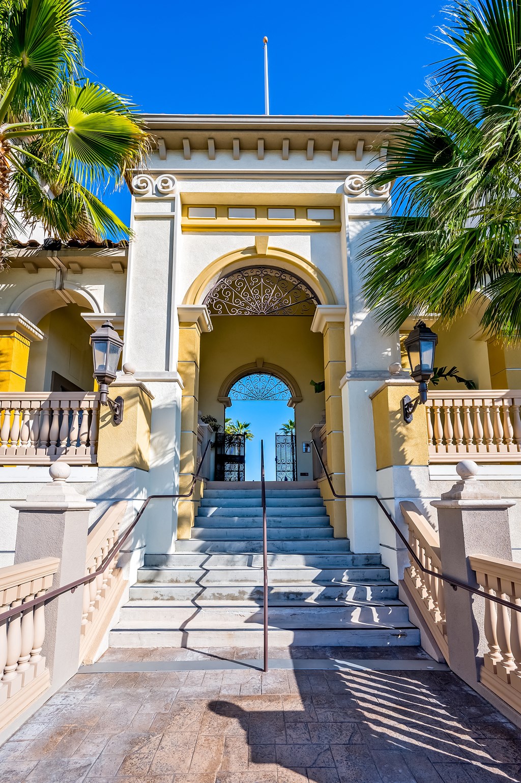 a building with a staircase and an archway with palm trees on either side
