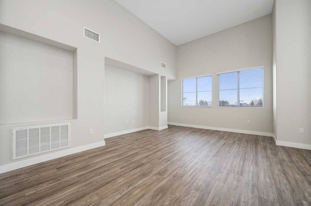 an empty living room with wood floors and a window