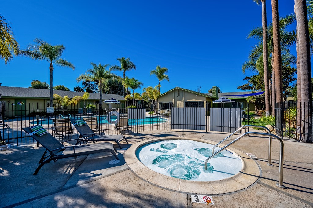 A hot tub sits in the middle of a pool surrounded by palm trees. A hot tub sits in the middle of a pool surrounded by palm trees.