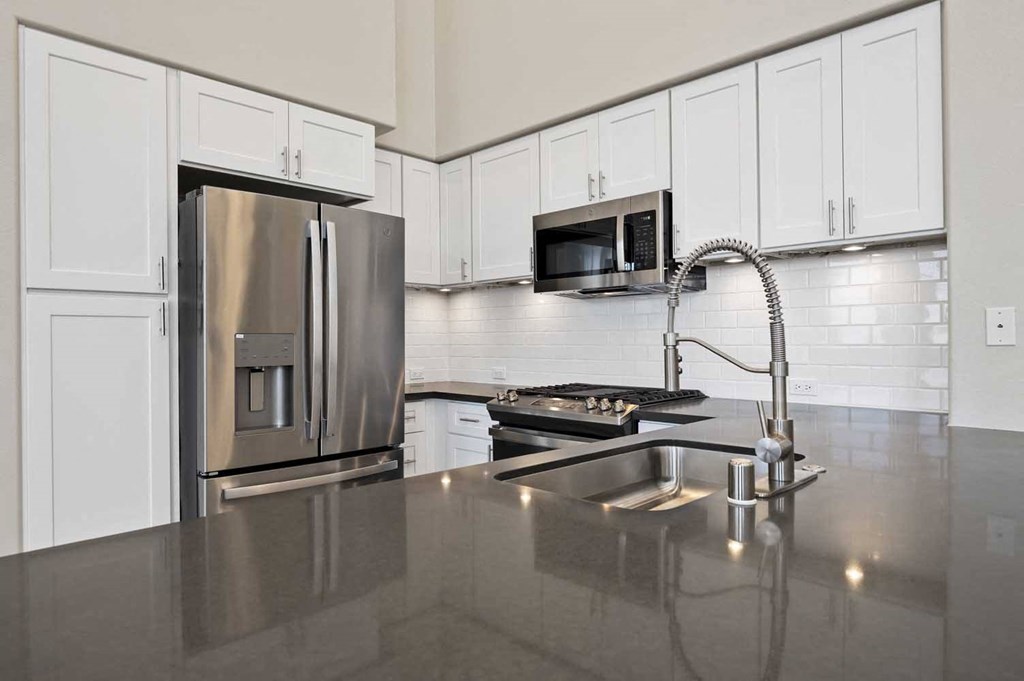a kitchen with a sink and a stainless steel refrigerator
