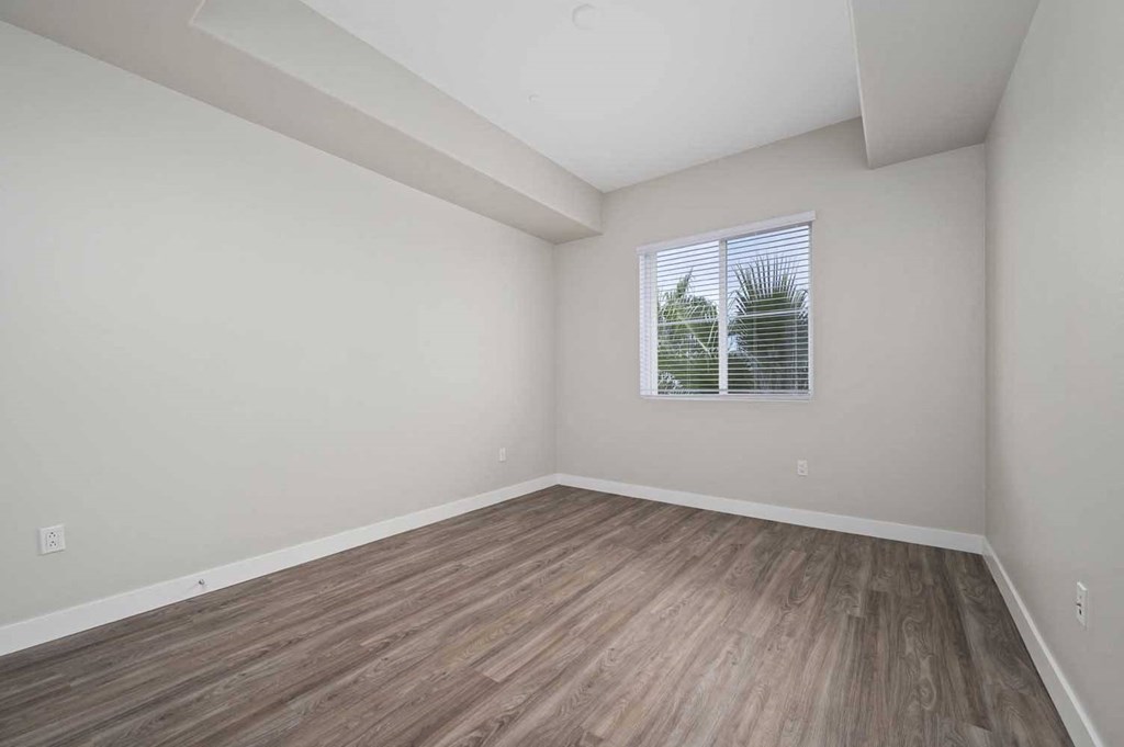 an empty living room with wood floors and a window