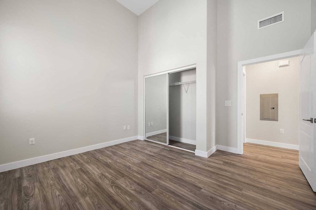 an empty room with white walls and wood flooring and a closet