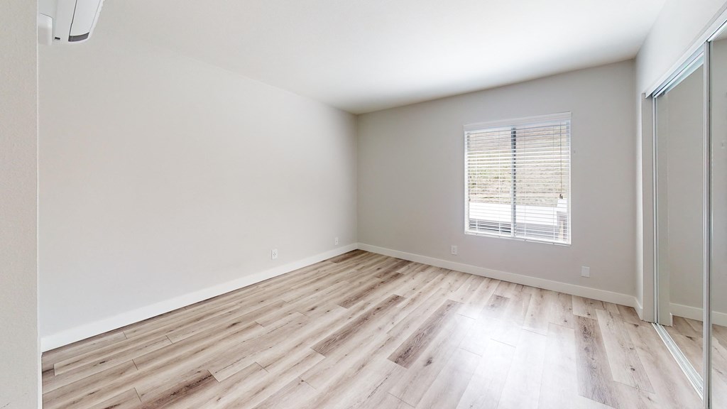 an empty room with wood flooring and a window