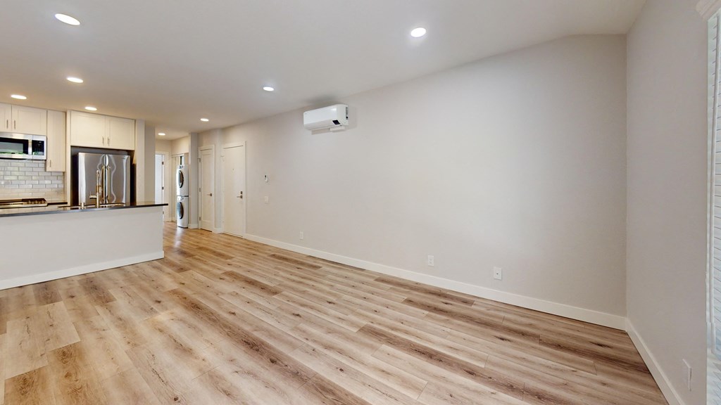an empty living room and kitchen with wood flooring