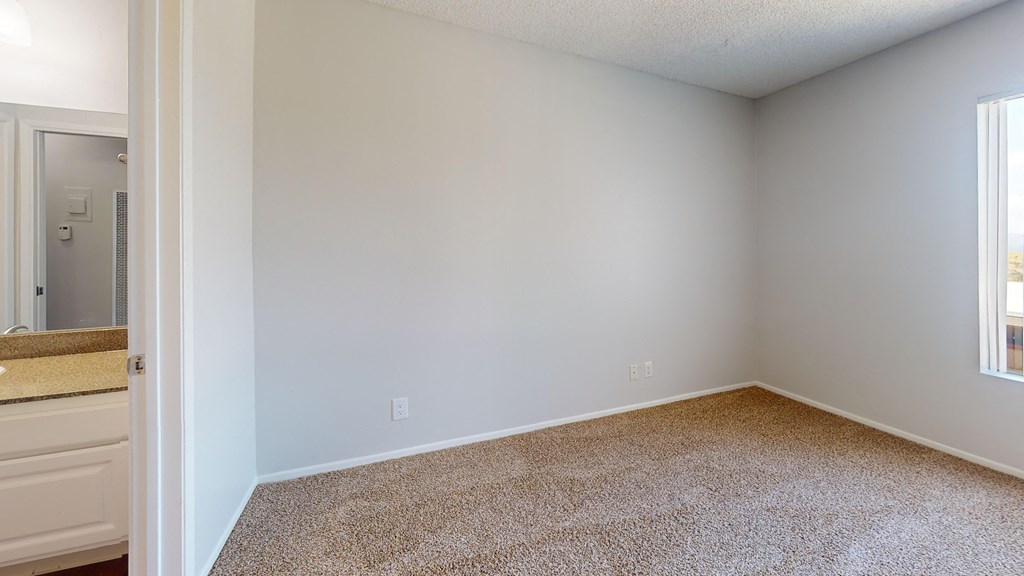 an empty room with a bathroom and a window