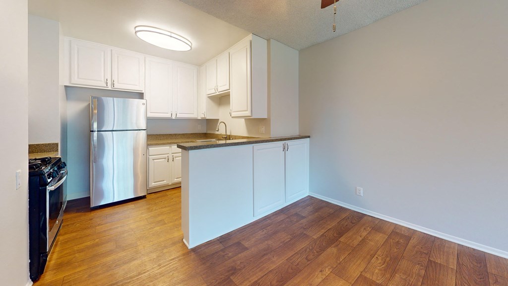 an empty kitchen with white cabinets and a stainless steel refrigerator