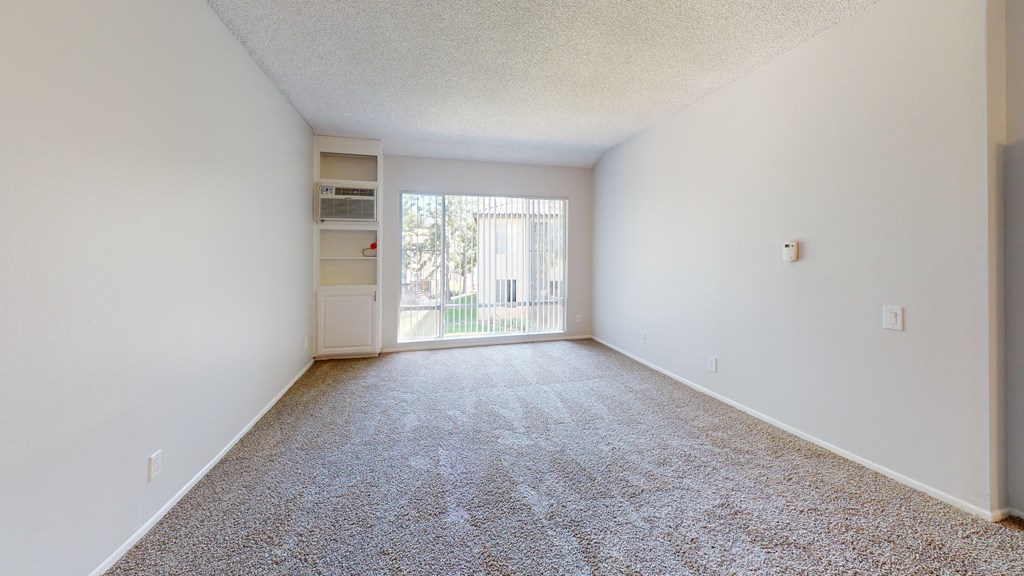 a spacious living room with carpet and a door to a balcony at Charter Oaks Apartments, California, 91360