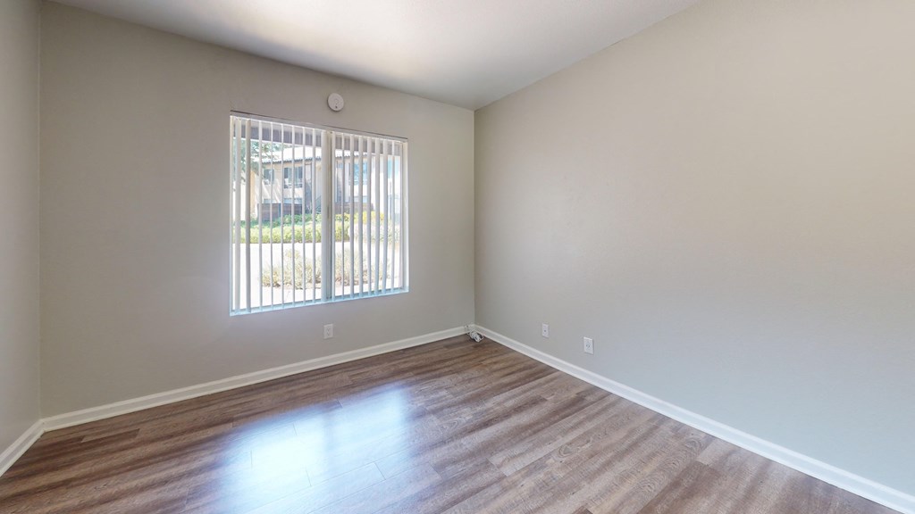 an empty living room with wood floors and a window