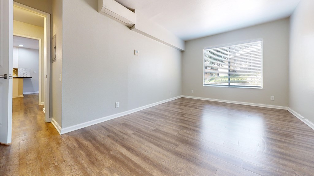 an empty living room with wood floors and a window