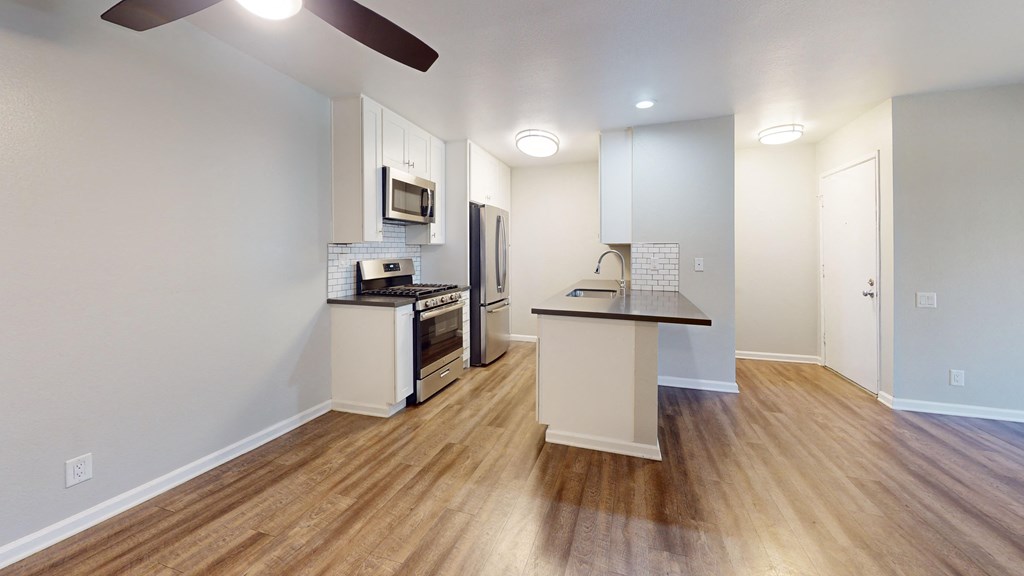 a kitchen with an island and stainless steel appliances and a hard wood floor