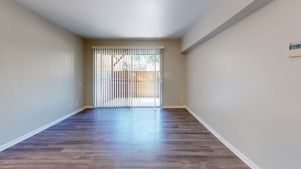 the spacious living room of an empty house with a large window