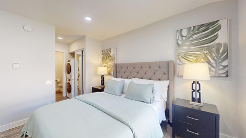 a bedroom with a large white bed and a painting on the wall at Charter Oaks Apartments, California