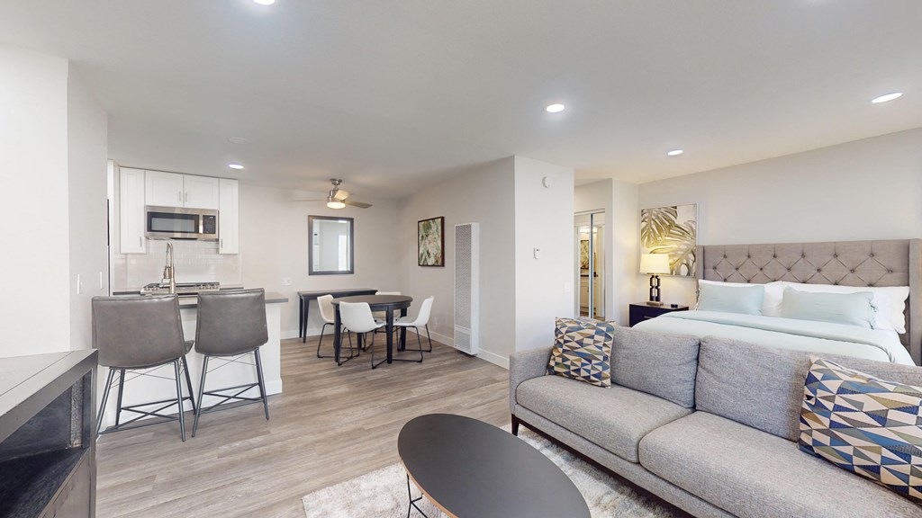 a living room with a couch and a kitchen with a bed