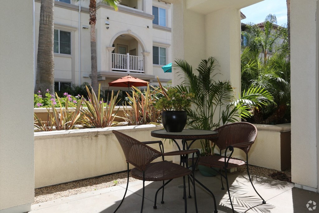 a patio with a table and chairs in front of a building