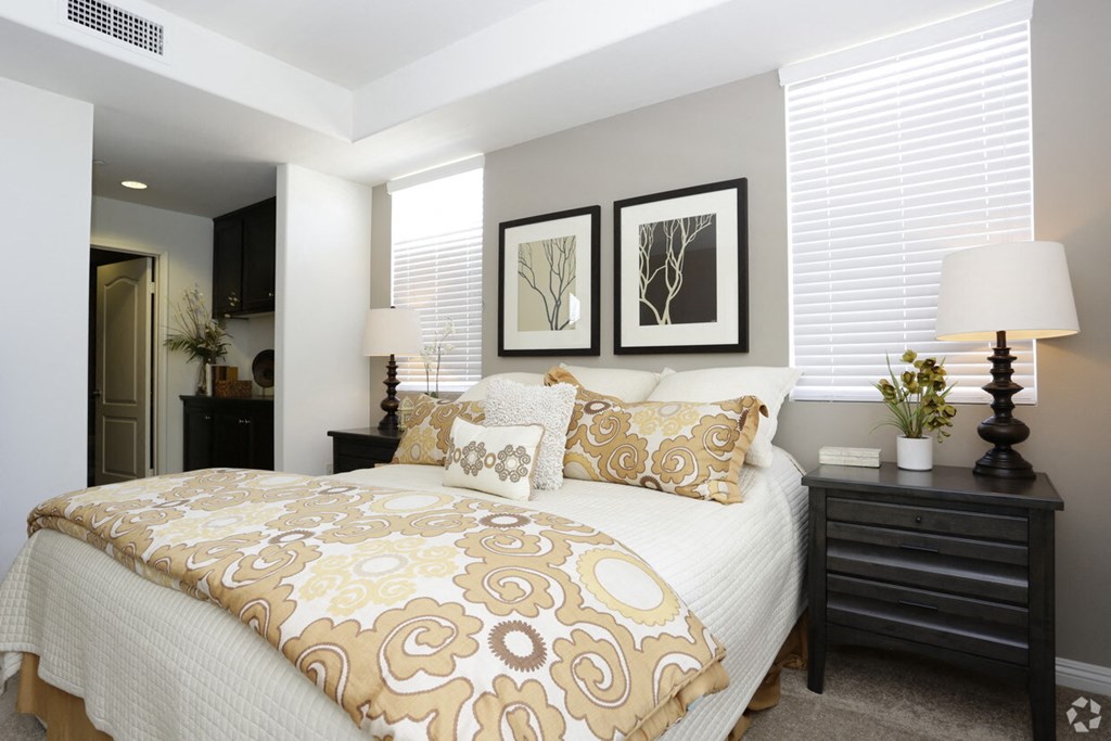 a bedroom with a bed with tan and white pillows