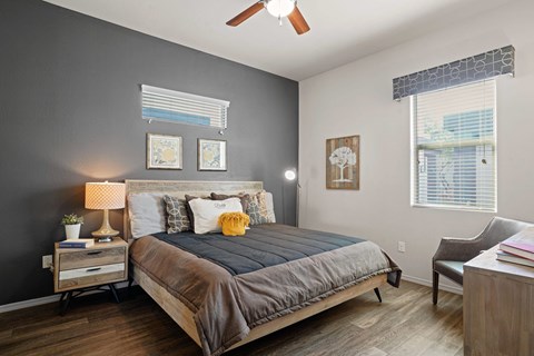 A bedroom with a bed, nightstand, chair, and pictures on the wall.
