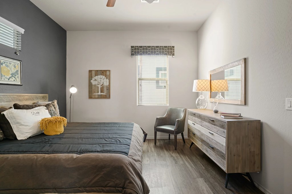 A bedroom with a bed, chair, and dresser.