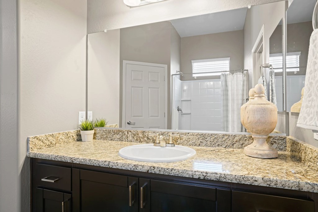 A bathroom with a granite countertop and a white sink.
