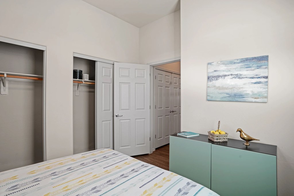 A room with a bed, a cabinet, and a painting on the wall.