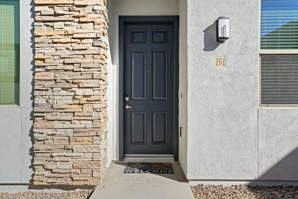 A house with a black door and a stone pillar on the left.