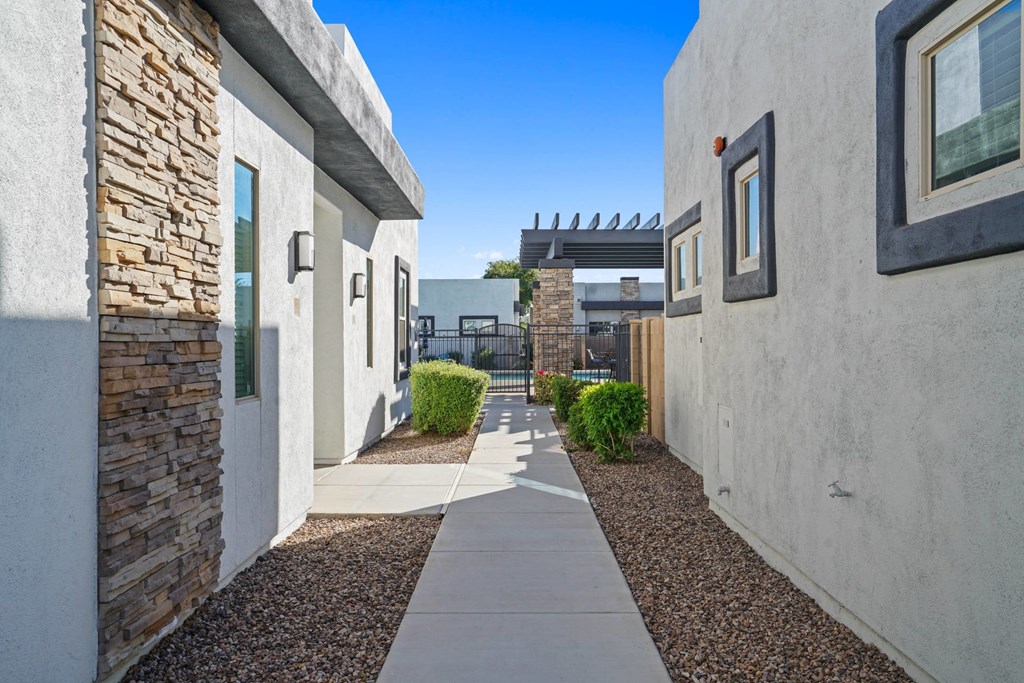A narrow alley with a stone wall on the left and a white wall on the right with a window.