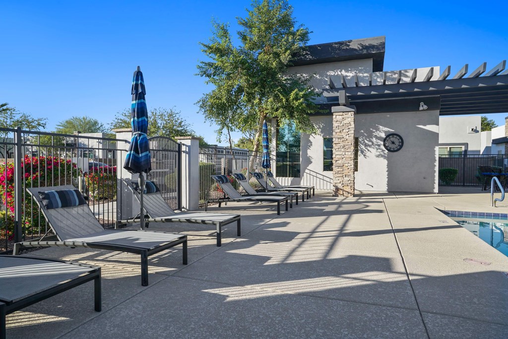 A poolside area with sun loungers and a shade structure.