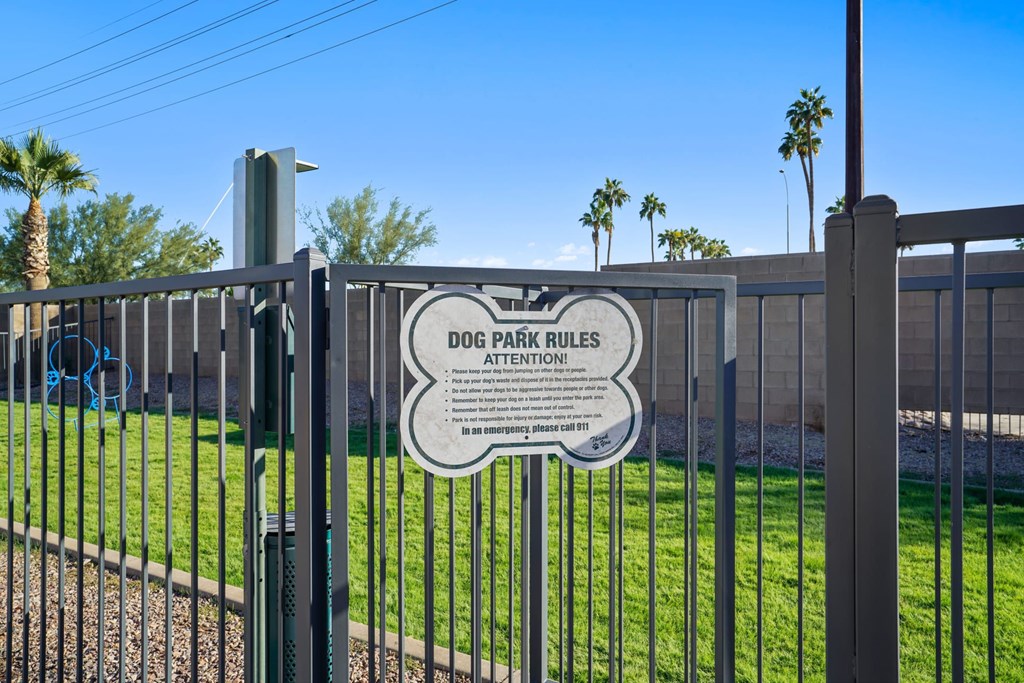 A sign on a fence that says Dog Park Rules Attention.