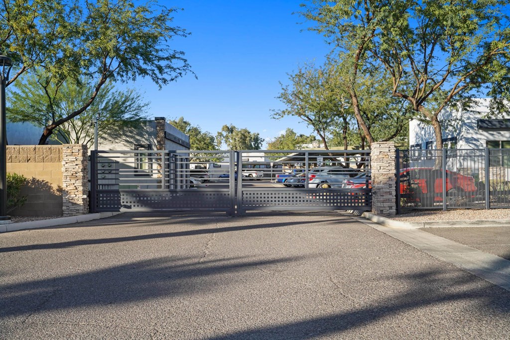 A gated entrance to a parking lot with a building in the background.