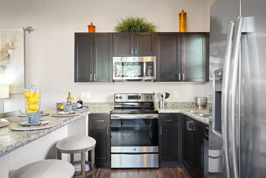 A modern kitchen with dark wood cabinets and stainless steel appliances.