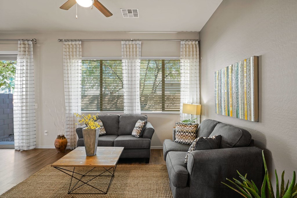 A living room with a grey couch, a coffee table, and a painting on the wall.