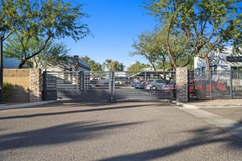 A gated entrance to a parking lot with a building in the background.