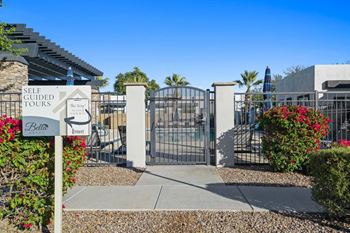 A sign for self-guided tours stands in front of a gated entrance.