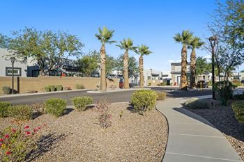 A pathway leads through a landscaped area with palm trees and shrubs.
