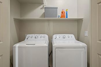 Two white front loading washing machines in a small laundry room.
