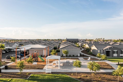 A playground area in a residential neighborhood with houses in the background.