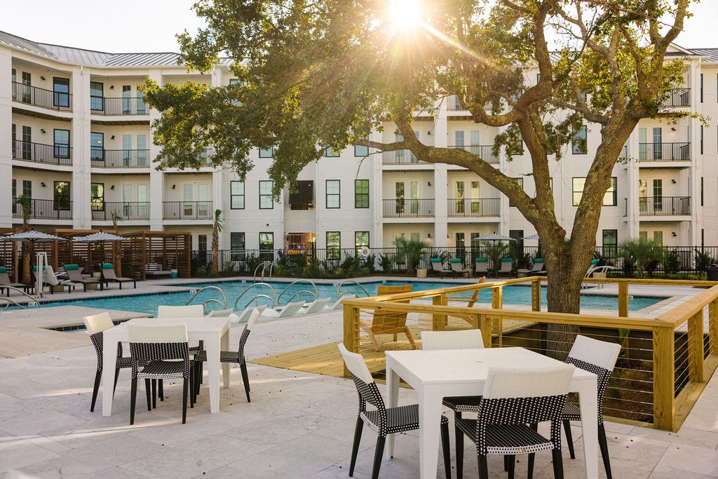 A sunny day at the poolside with chairs and tables.