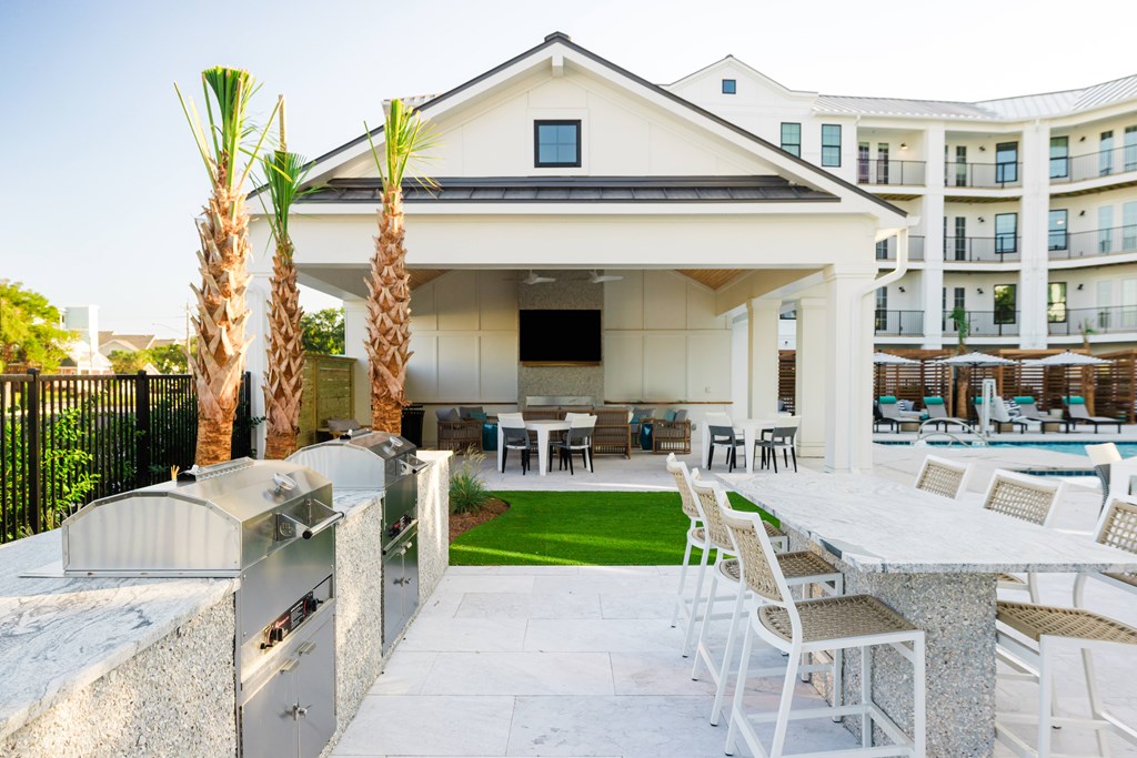 A white building with a black fence and palm trees in front.