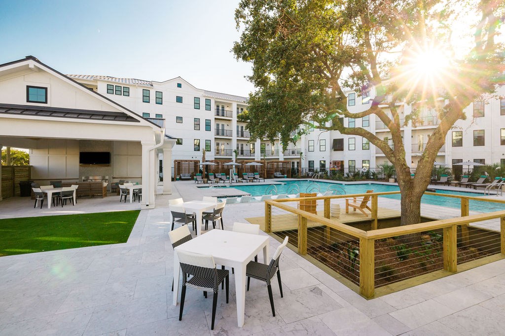 A sunny day at the poolside with tables and chairs.