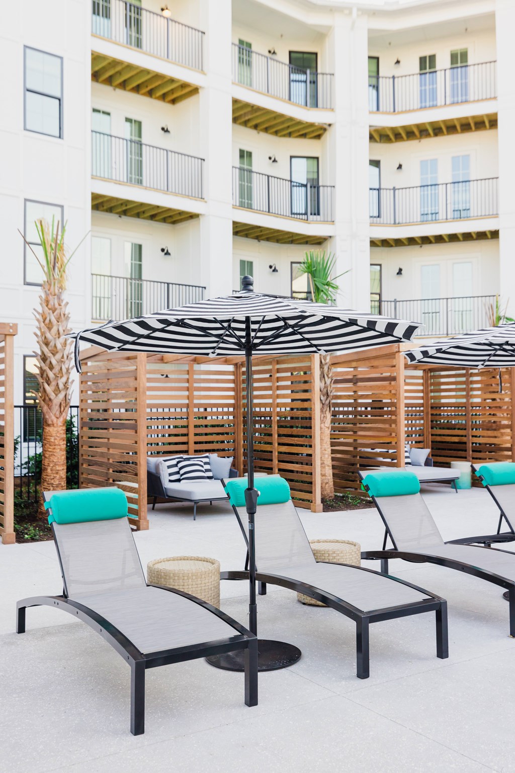 A patio with chairs and umbrellas in front of a building.
