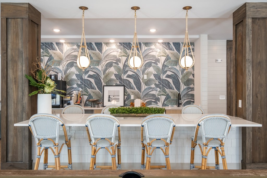 a bar with blue chairs and a wall with a mural of palm trees