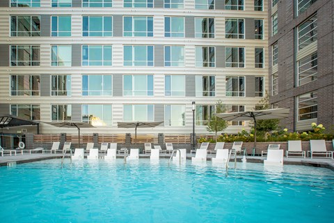 a swimming pool with white chairs in front of a building