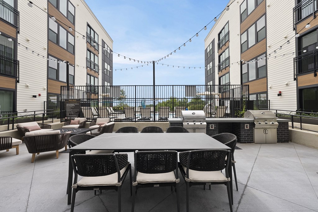 a large patio with a table and chairs in front of an apartment building