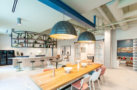 a dining room with a wooden table and chairs and a kitchen in the background