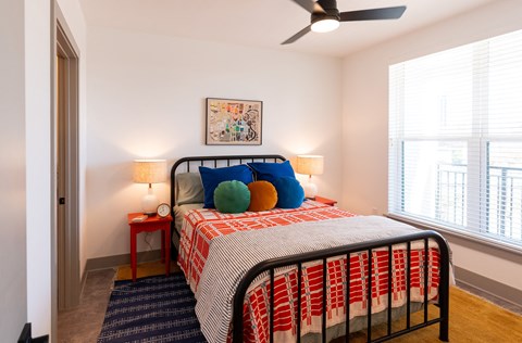 a bedroom with a bed and two windows and a ceiling fan