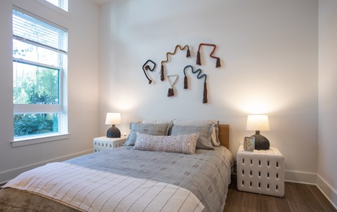 A bedroom with a bed, two lamps, and a wall decoration.