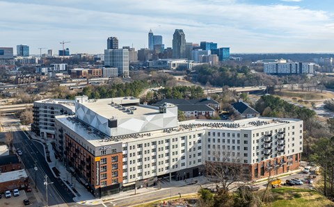A large white building with a lot of windows is in the foreground of a cityscape.